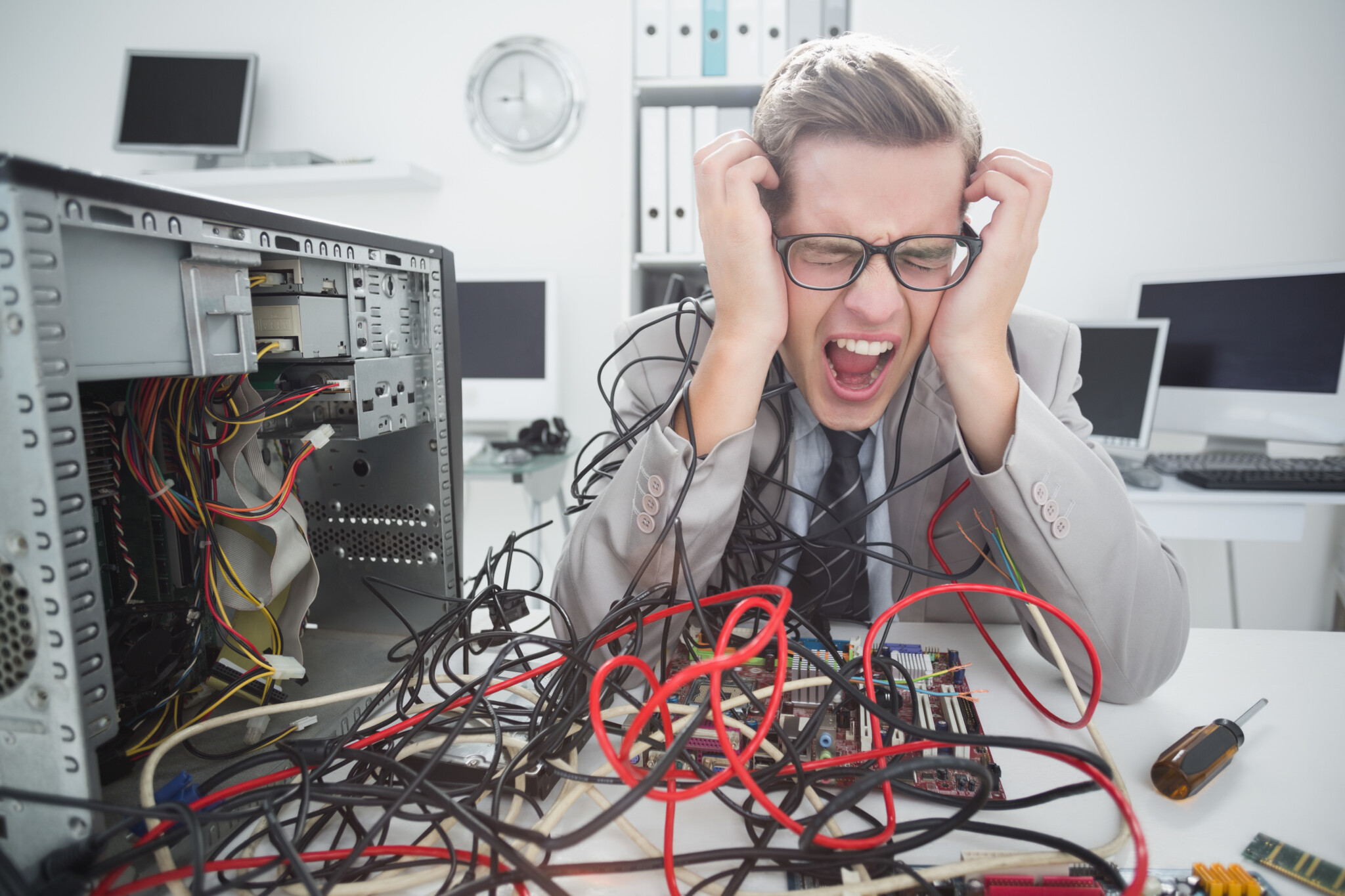 Stressed computer engineer working on broken cables in his office